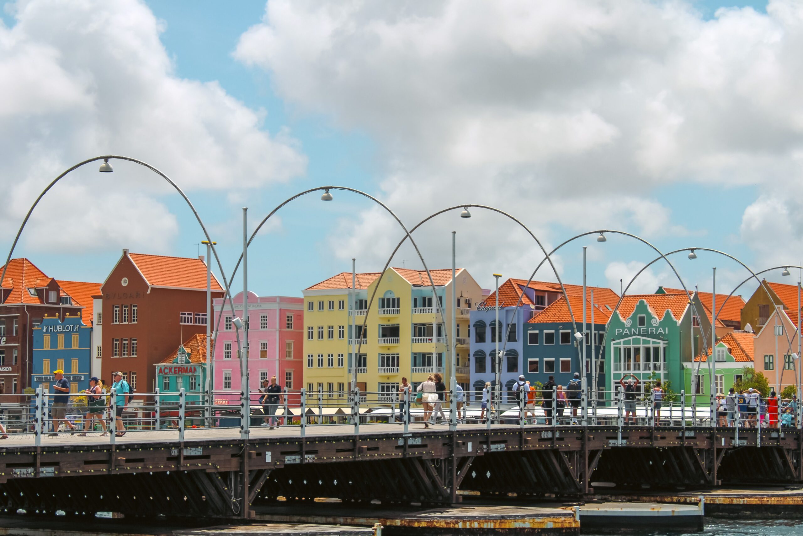 Toeristen op de Koningin Emmabrug met de gekleurde huizen van Willemstad op Curaçao