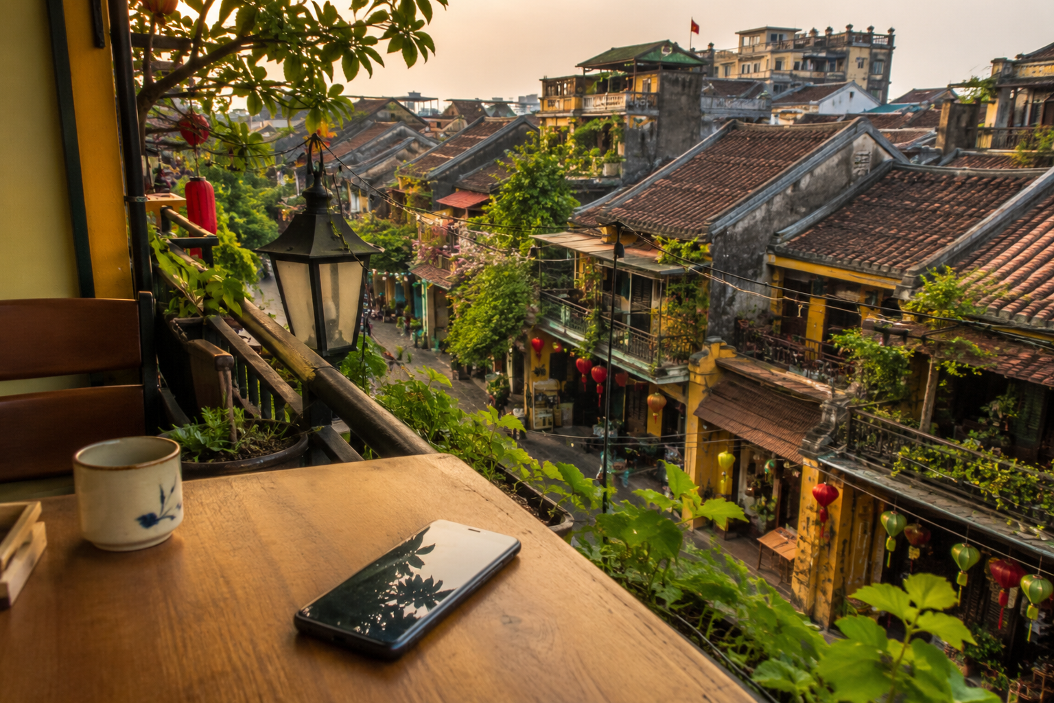 Smartphone op een houten tafel bij een rooftop café in Vietnam met Vietnamese architectuur op de achtergrond